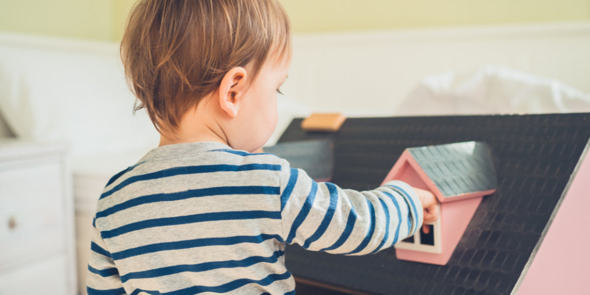 Erziehung ohne Klischees: Bub spielt mit Puppenhaus