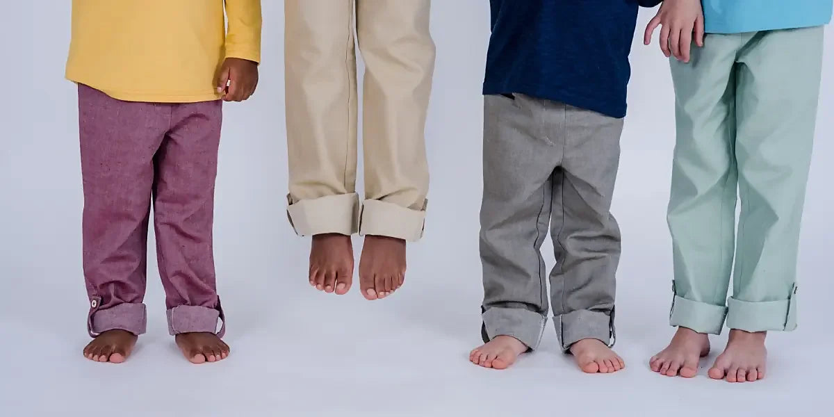 Vier Kinder bzw. deren Beine mit pauaGrow Hose, ein Kind springt