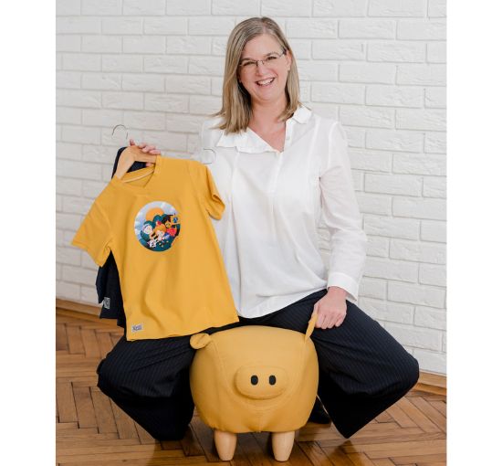 Conny Aigenberger mit pauakids Shirt auf gelbe Sitz-Schwein für Kinder