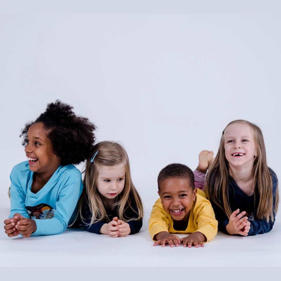 Vier Kinder liegen am Boden, auf Brust, Kopf voran und lachen