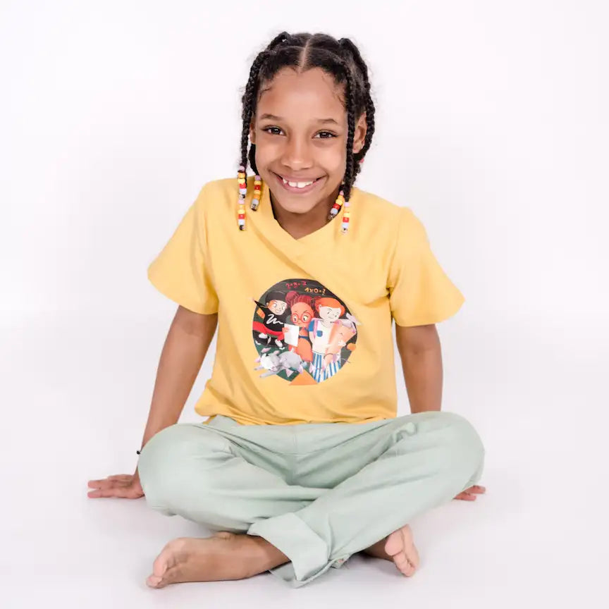 gelbes Schulstart Shirt getragen von lachendem Kind, sitzt im Schneidersitz