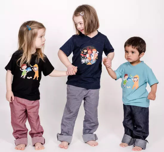 Drei Kinder mit pauakids Kleidung halten sich an Händen, in der Mitte Kind mit Down Syndrom