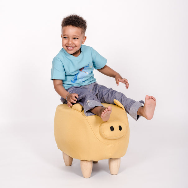 Lachendes Kind mit pauakids Hose auf Hocker der aussieht wie ein Schwein