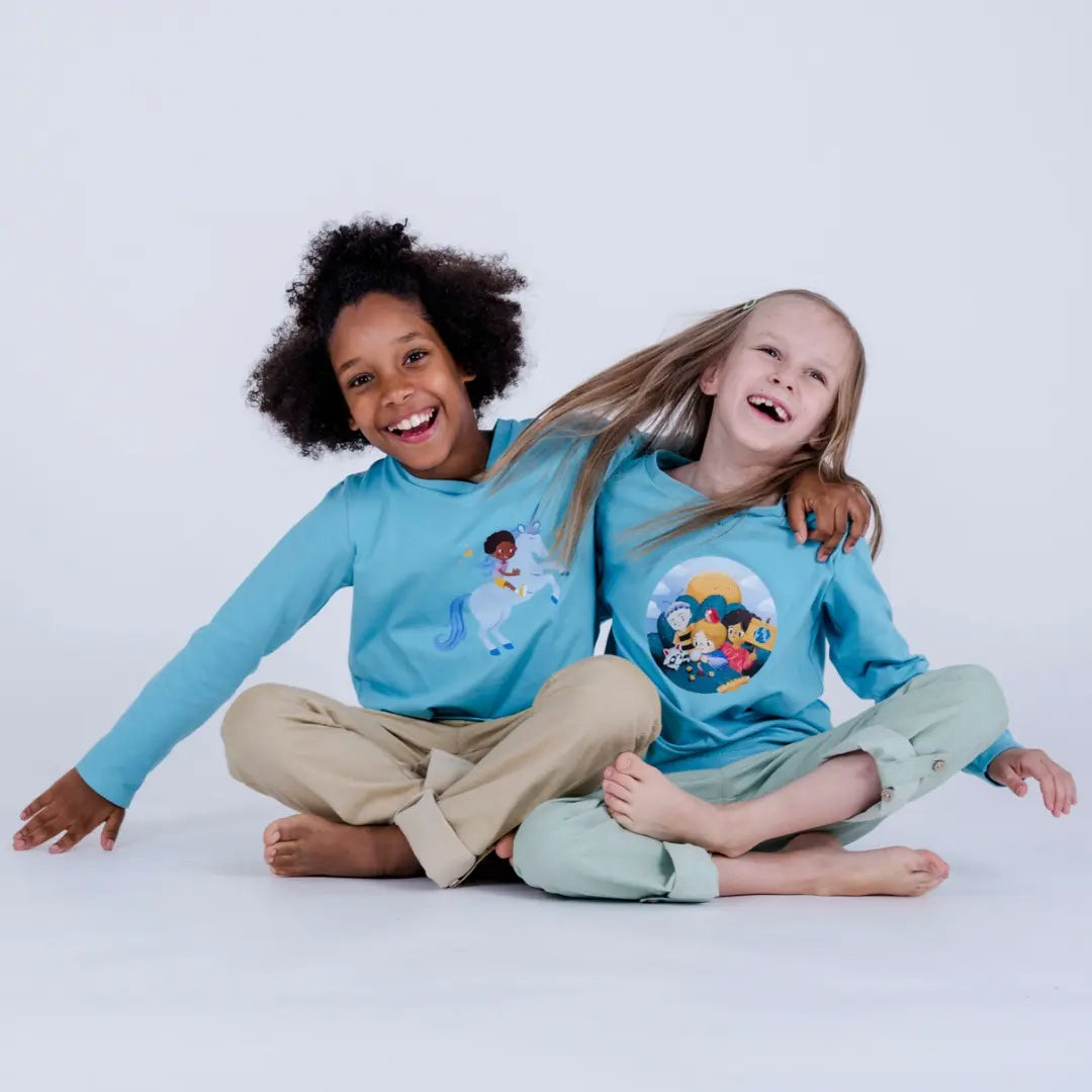 Zwei Kinder sitzend, umarmen einander und schunkeln - mit pauakids Kleidung